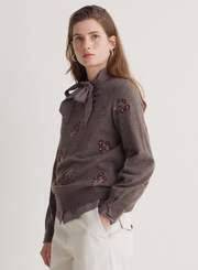 Woman wearing a brown sweater with floral embellishments on a white background