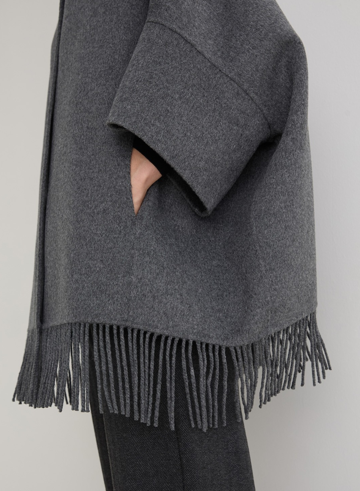 Gray poncho with fringes on a plain background