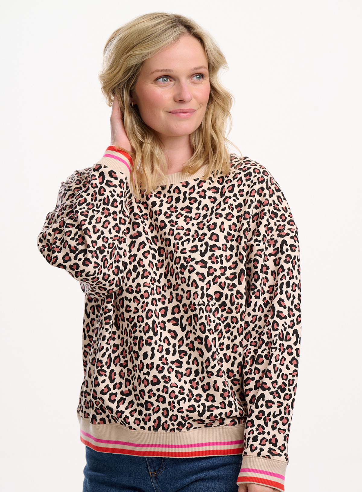 Woman wearing a leopard print sweater with pink accents on a white background