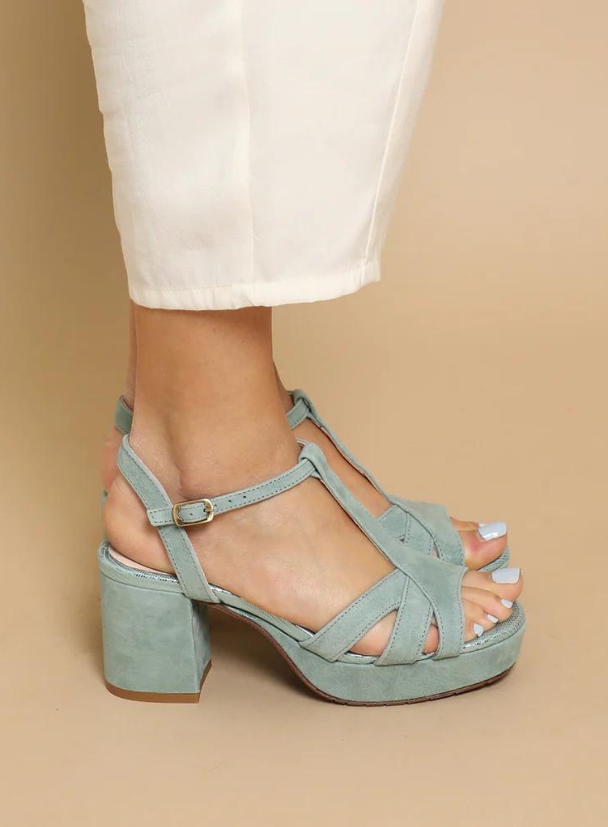 Model styling a pair of white ankle length trousers with the Esska Charlie Mint Suede Heels on a beige backdrop. In side profile showcasing the adjustable straps of these fisherman sandals.