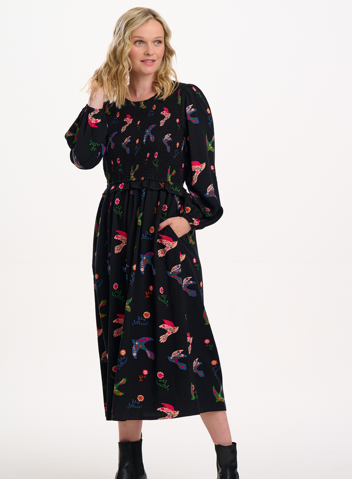 Woman wearing a black dress with colorful floral and abstract patterns on a white background