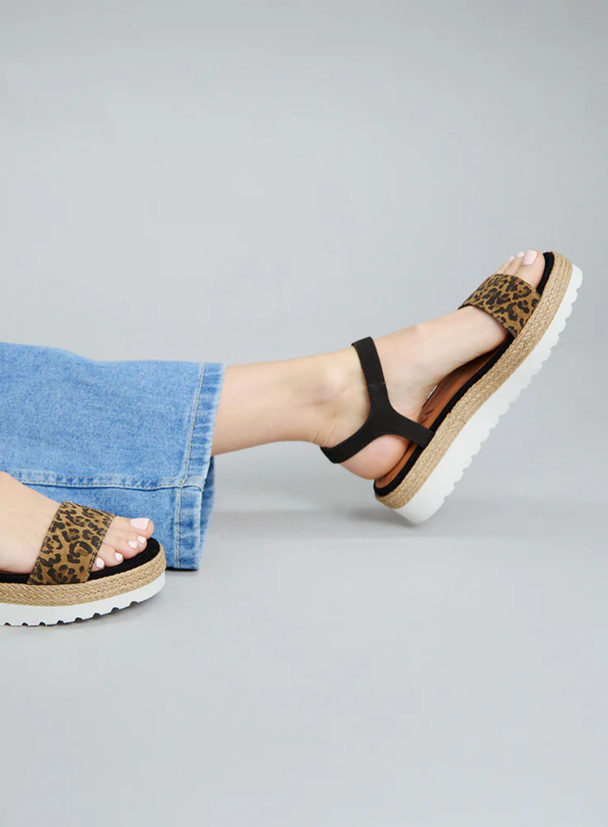 Model wearing a pair of light wash blue denim jeans with the Esska Uma Leopard Print Espadrille Sandals. Side shot showcasing the platform sole.