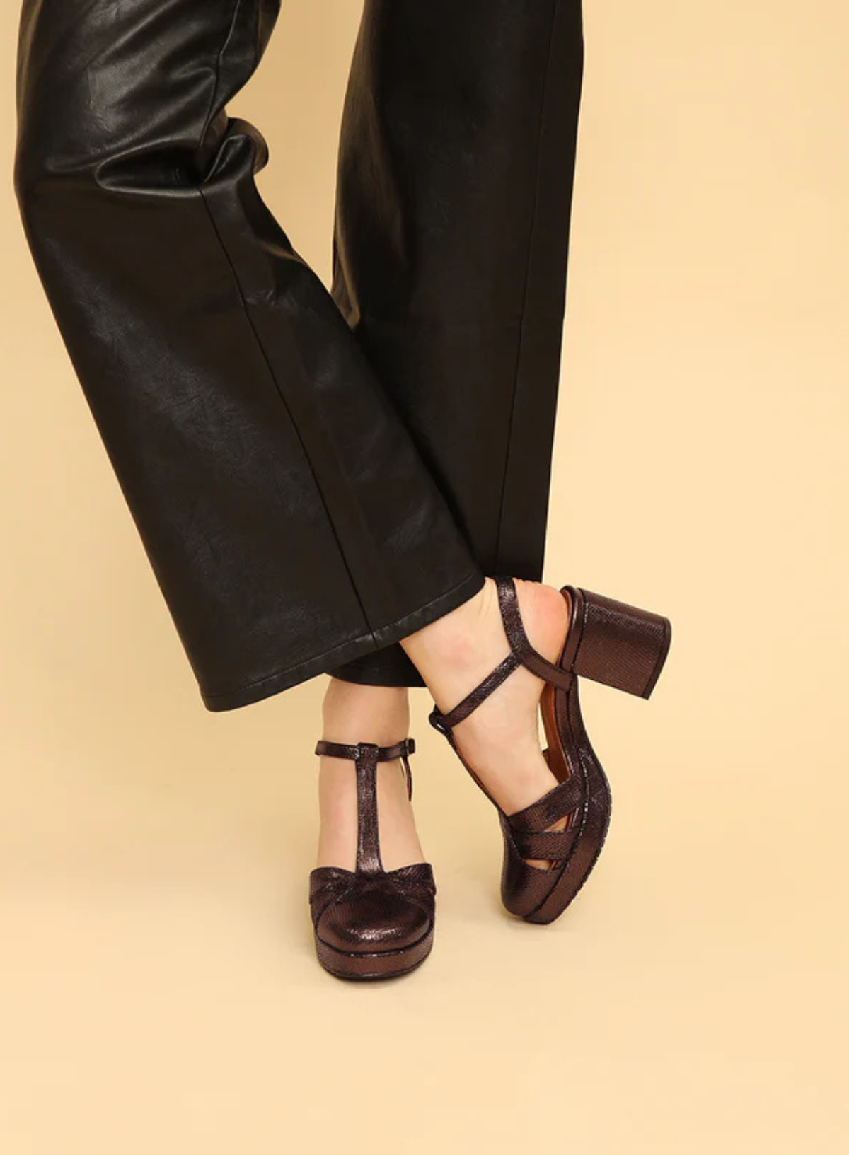 Model wearing the Esska Celeste Dark Brown Metallic Platform Block Heels styled with black leather wide leg trousers. Front side profile showcasing the  closed toe, straps and block heel.
