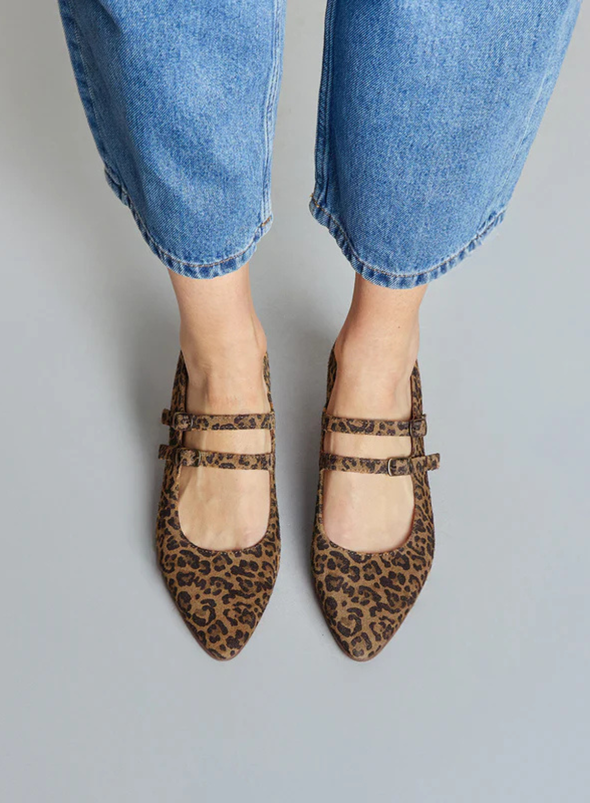 Model wearing the Esska Laura Low Leopard Heels with denim jeans against a grey background. Front shot showcasing straps and pointed toe shape.