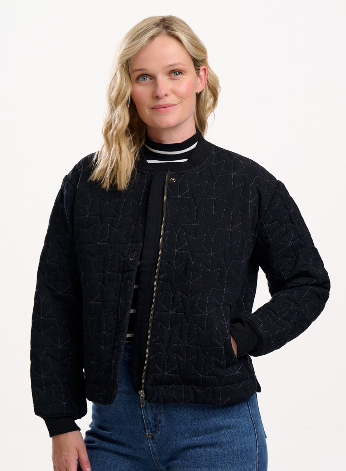 Woman wearing a black quilted jacket with a white background