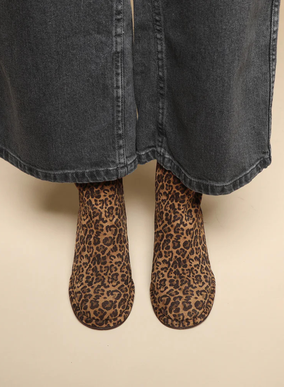 Model wearing the Esska Mona Leopard Print Boots with wide leg charcoal jeans. Front shot showcasing the all over leopard print and round toe shape of these leopard print ankle boots.