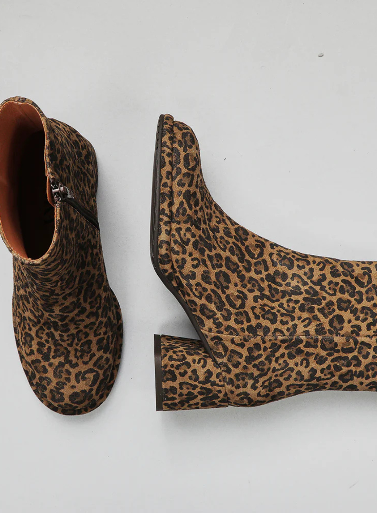 Pair of Esska Mona Leopard Print Boots on a grey background. Overhead and side shot showcasing the round toe shape, the block heel and all over print of these ankle boots. 