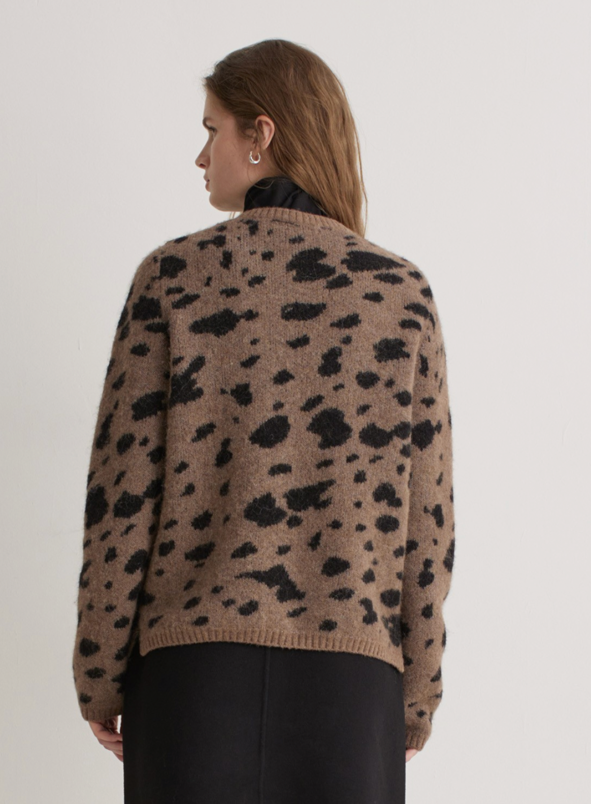 Person wearing a leopard print sweater against a plain background
