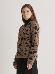 Woman wearing a brown sweater with black leopard print pattern on a white background