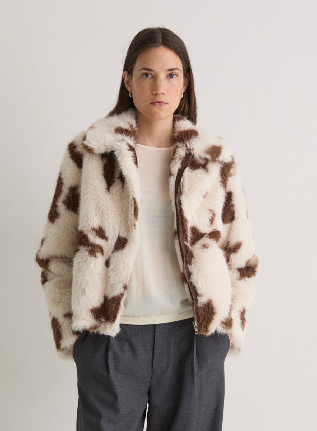 Person wearing a brown and white patterned coat on a plain background