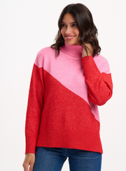 Woman wearing the Sugarhill Brighton Winona Pink Red Colour Block Roll Neck Jumper on a white background