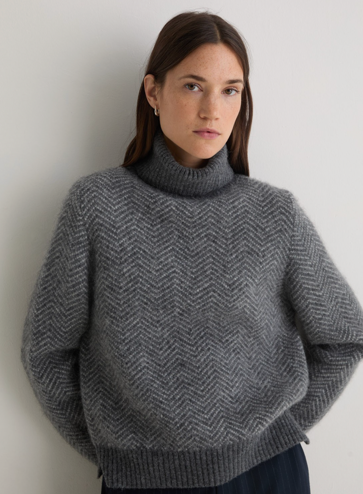 Woman wearing a gray textured sweater against a plain background