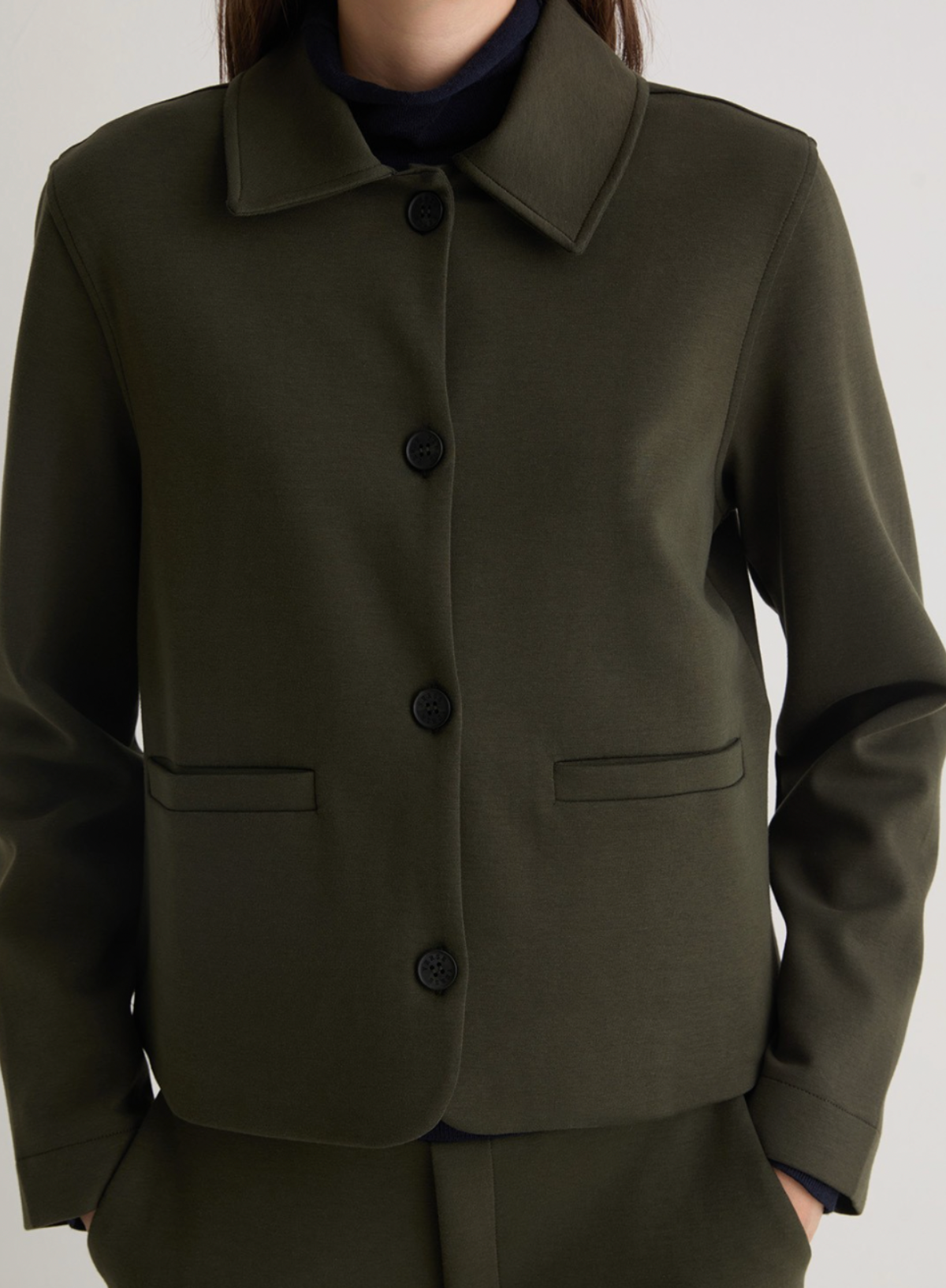 Green coat with black buttons on a neutral background