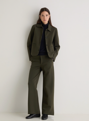 Person wearing a green jacket and trousers on a plain background