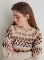 Woman wearing a patterned sweater against a plain background