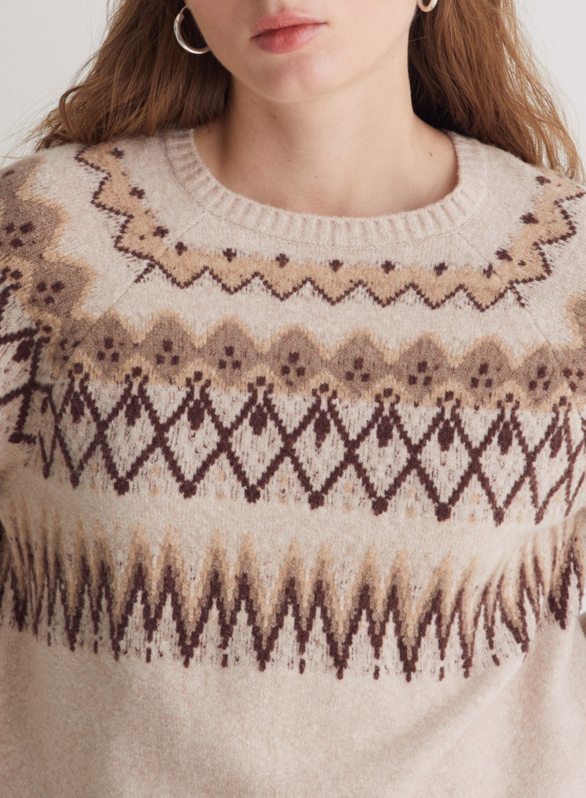 Close-up of a person wearing a patterned sweater with a neutral background